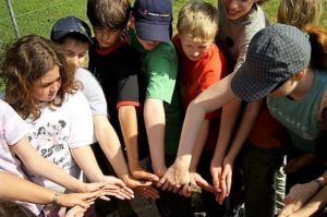 Erlebnispädagogik-Ausbildung. Kinder legen ihre Hände aneinander