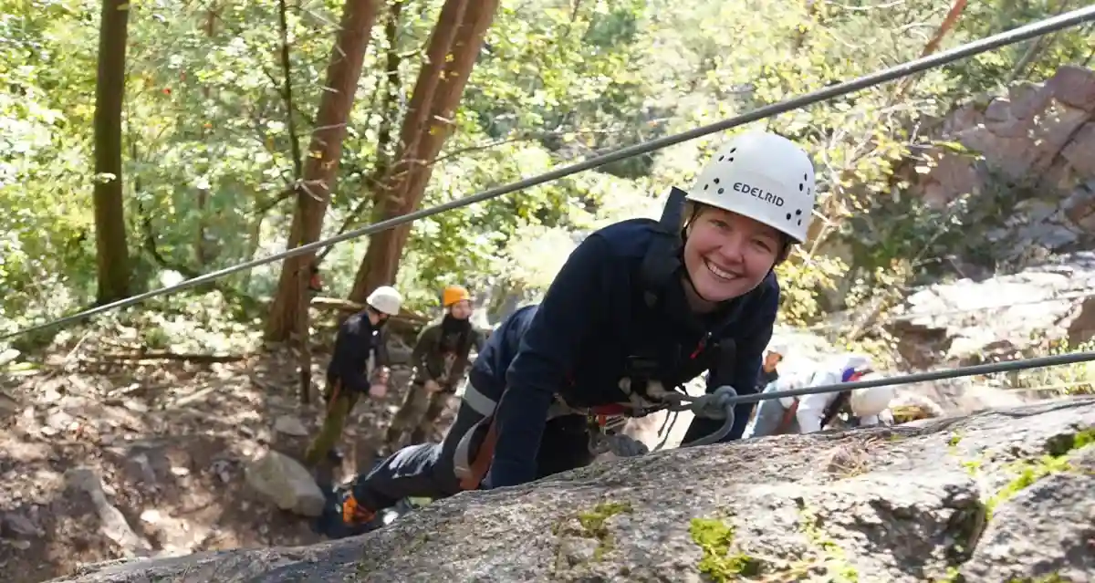 Frau klettert während einer Kletteraktion während der Erlebnispädagogik Ausbildung, Erlebnistherapie Ausbildung und Outdoorguide Ausbildung
